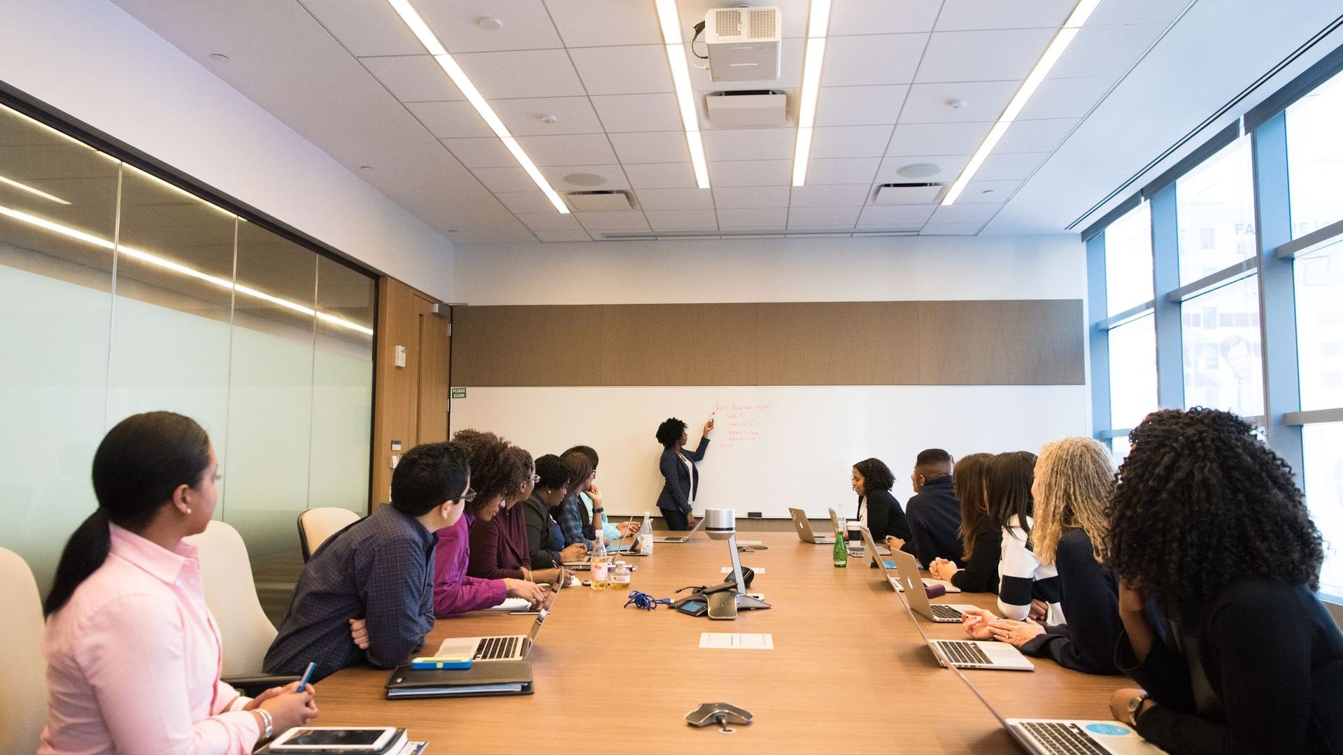 Professionals seated around a boardroom table beside a wall of windows