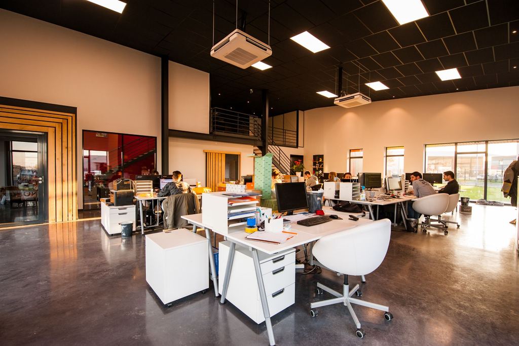 Open plan workplace interior with desks, natural light and meeting areas